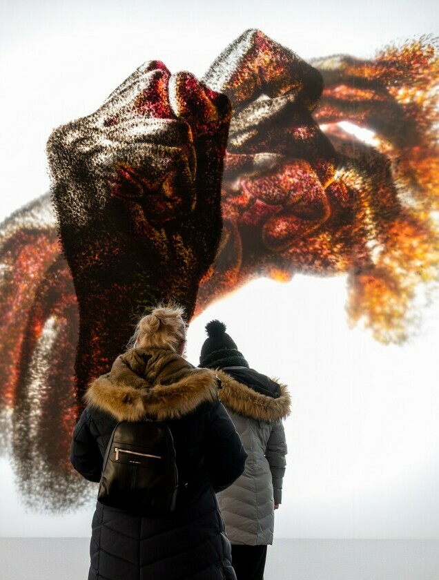 Two individuals stand in front of an artwork.