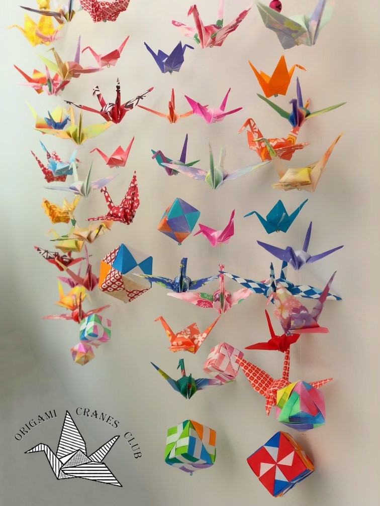 a bunch of origami cranes hanging on a wall