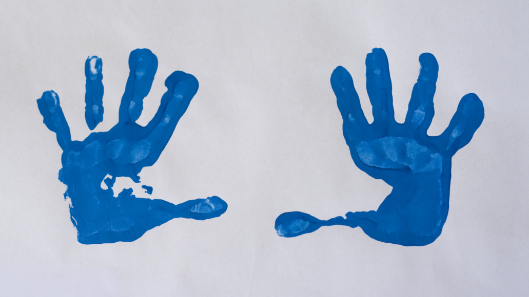 two handprints in blue paint on paper