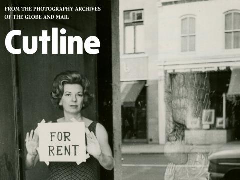 Black and white photo - Woman holding For Rent sign in window