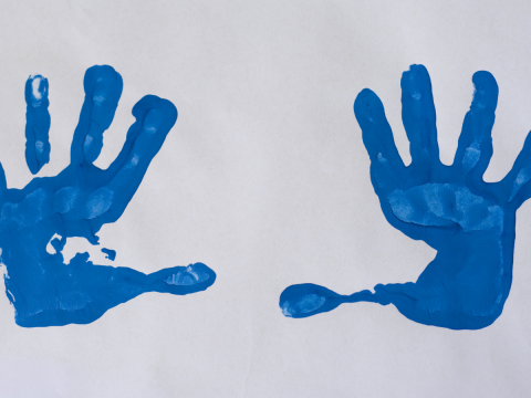 two handprints in blue paint on paper