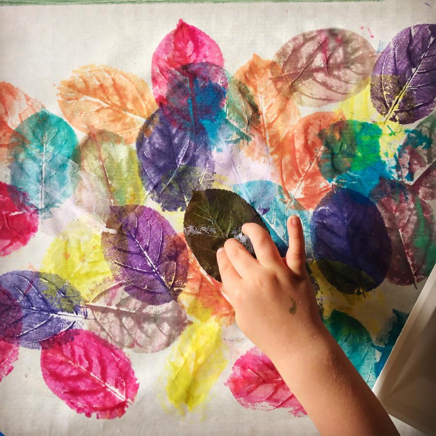 Image ID: Printed images of leaves made by painting and stamping a leaf collected from the playground. We painted the leaf with tempera paint in different colours while layering the impressions from lightest (yellow) to darkest (indigo).